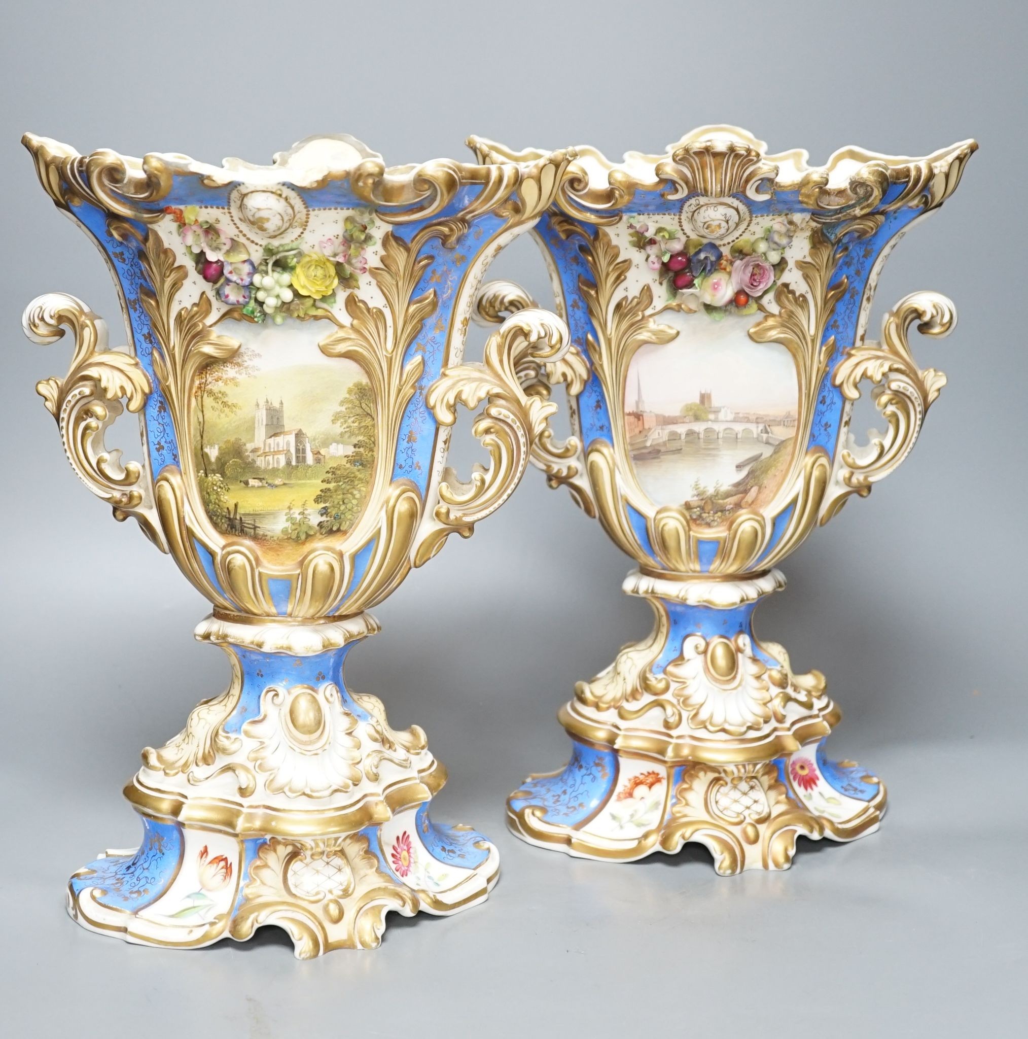 A large pair of 19th century Grainger & Co. vases with scenes of Worcester and Malvern on a blue ground, 34 cms high.